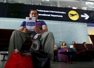 A man reads a Zika virus flyer from an information campaign by the Chilean Health Ministry at the departures area of Santiago’s international airport, Chile. Ivan Alvarado/Reuters