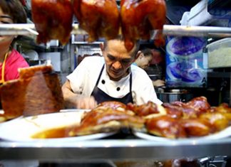 chan hon meng is chopping the chicken in his small local street food vendor