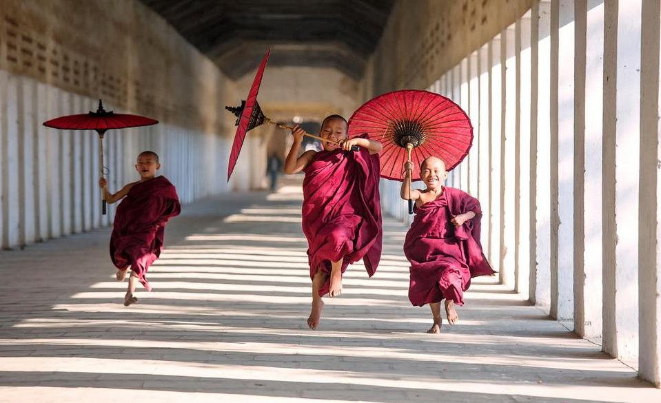 Novice monks with umbrellas running at temple, Bagan, Myanmar