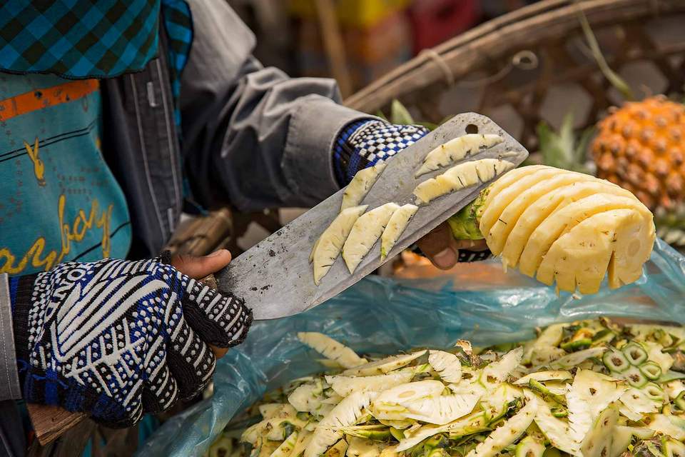 Cutting fresh pineapple at the Russian market in Phnom Penh, Cambodia. © Ulli Maier