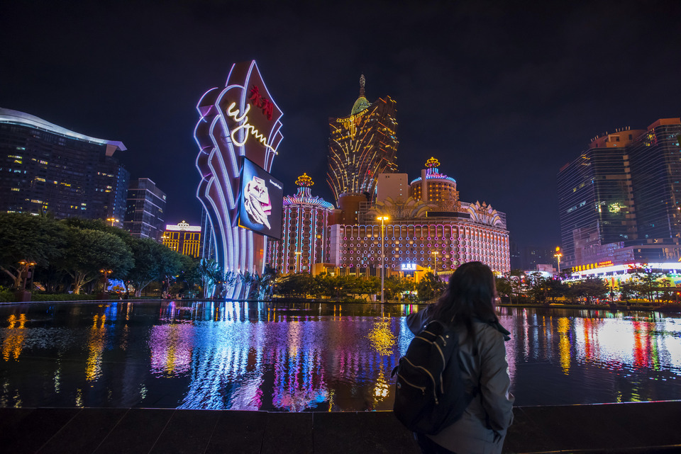 A pedestrian walks past signage for the Wynn Macau casino resort