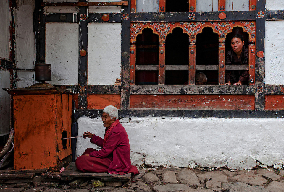 An elderly woman turns a prayer wheel at Kyichu Lhakhang in Paro, Bhutan.