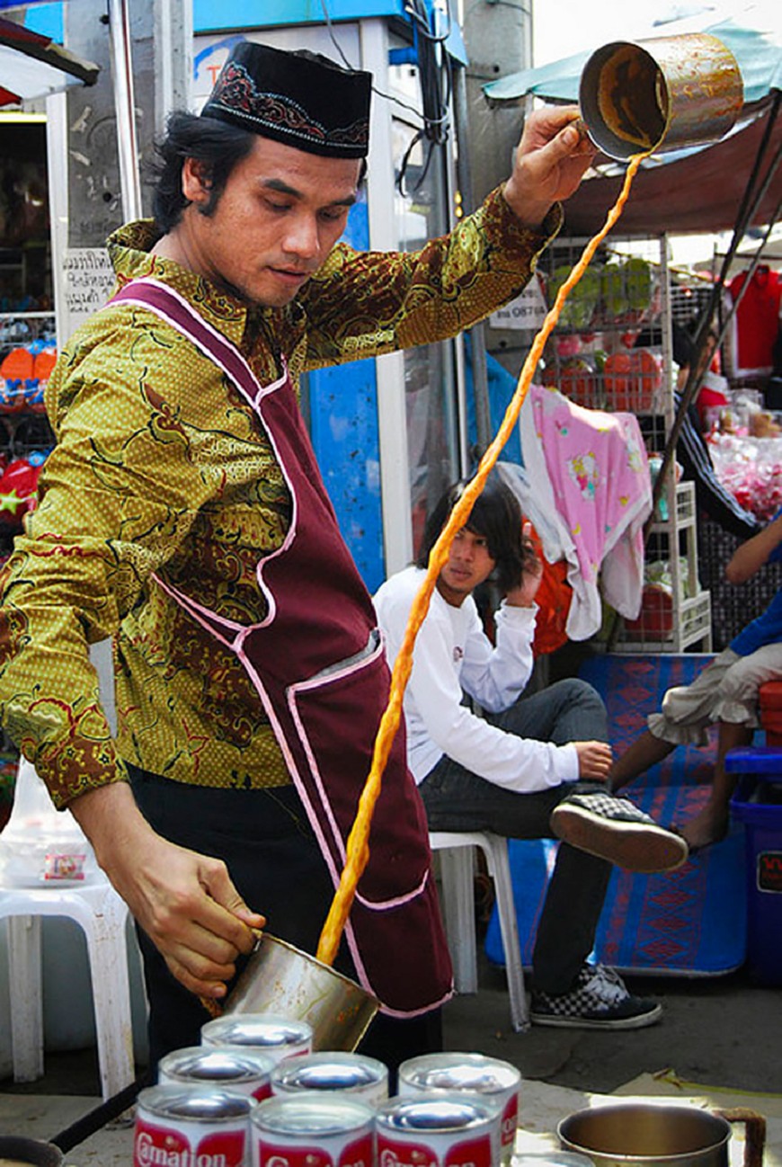 An artisan is performing how to making the traditional Teh Tarik tea.